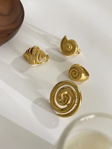 Detailed view of four golden stainless steel rings with shell and spiral cutout patterns