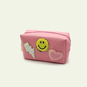 Close-up of pink PU makeup bag with chenille patches of lightning, smiley, and heart