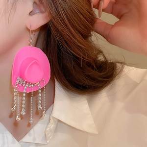 Detailed close-up of pink cowboy hat earring with sparkling rhinestone fringe on model