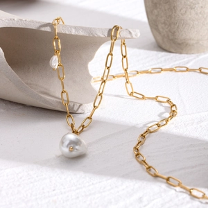 Detailed close-up of 18k gold-plated irregular baroque pearl necklace on stone display