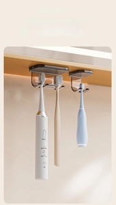 Detail of wall-mounted toothbrush holder with transparent dual slots and silver backing