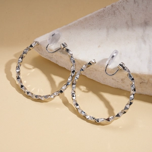 Macro detail of geometric diamond-cut silver clip-on earrings with secure silicone pads