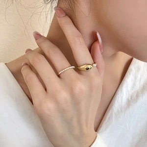 Minimalist 2-piece gold-plated ring set with pearls worn on a model's hand in soft light