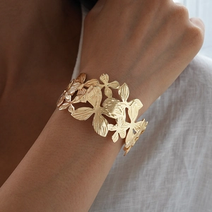 Detailed macro shot of a wide gold cutout floral cuff bracelet worn by a model