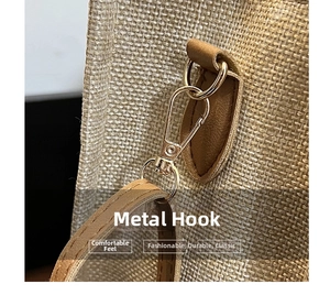 Detailed close-up of golden metal swivel hook and textured linen fabric of the handbag