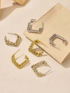 Close-up of triple-layered twisted hoop earrings in gold and silver mixed metal finish