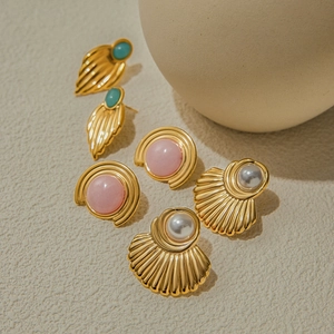 Macro detail of gold earrings featuring blue stone, pink gem, and white pearl