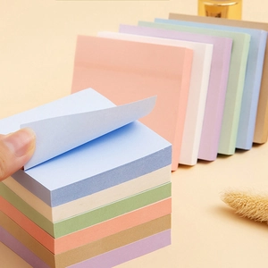 Primer plano de una mano pelando una nota adhesiva 3x3 de un set de color pastel