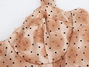 Dettaglio del tessuto in rete beige a pois con decorazioni di rose in tessuto 3D