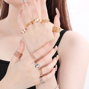 Detail shot of stacked gold, silver, and rose gold rings with heart and chain patterns
