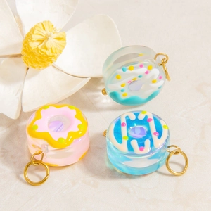 Detail of colorful resin donut pendants with gold metal rings on stone background