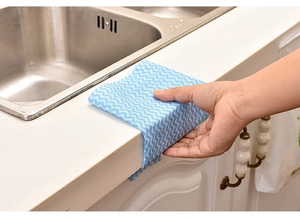 Blue wave pattern disposable cleaning cloth wiping a white marble kitchen countertop