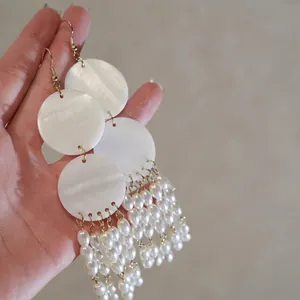 Macro view of shell discs and hanging imitation pearl tassels on drop earrings