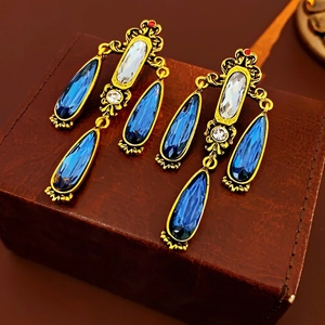 Orecchini pendenti vintage stile palazzo con cristalli blu intenso su fondo in pelle marrone