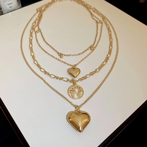Detailed macro view of triple-layered gold necklaces with heart and map pendants