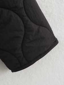 Macro detail of black quilted jacket showing wave stitching and premium nylon texture