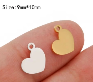Macro shot of 9x10mm gold and silver heart pendants displayed on a fingertip for DIY jewelry