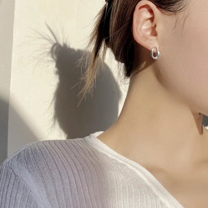 Detail of minimalist S925 sterling silver oval hoop earring on model with mirror finish