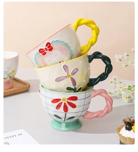 Detailed view of stacked ceramic mugs with hand-painted floral patterns and twisted handles