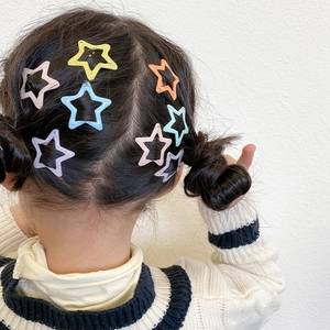 Detail shot of colorful star hair clips on a child's braided double bun hairstyle