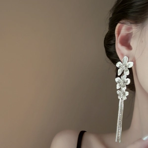 Detail of elegant silver flower tassel earrings with crystals on a female model