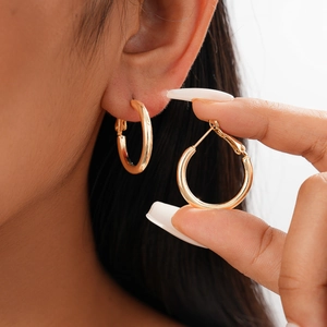 Minimalist geometric round metal hoop earrings in gold finish worn by model