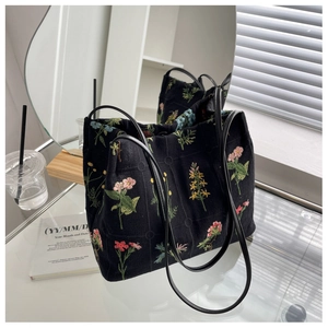 Detailed embroidery of colorful floral patterns on a high-capacity black canvas tote bag