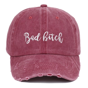 Macro detail of wine red distressed cotton cap with white Bad Bitch embroidery