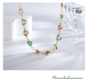 Detailed close-up showing micro inlaid colorful heart-shaped zircons on gold necklace
