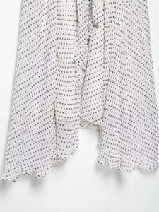 Detailed view of the elegant polka dot pattern fabric and draped hem on white dress