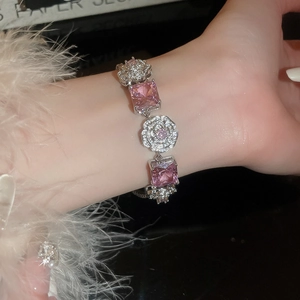 Close-up of silver bracelet with pink square gemstones and diamond camellia flower charms
