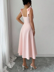 Detail van roze midi-jurk met verstelbare strikbandjes en elegante stoftextuur