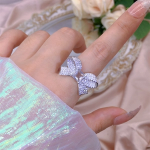 Close-up of zircon bow ring on finger with silver finish and square main stone detail