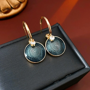 Detailed view of vintage gold flower earrings with green enamel and sparkling zircon stone