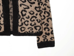 Close-up of leopard jacquard knit fabric with black ribbed cuffs and fuzzy texture