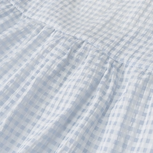 Close-up detail of light blue and white checkered pleated fabric texture on the blouse