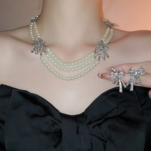 Close-up of triple-layer pearl necklace with rhinestone bows and matching earrings