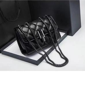 Dettaglio borsa a catena trapuntata nera con elegante chiusura rettangolare in metallo argento
