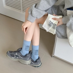 Mid-calf light blue cotton socks with black lettering in a minimalist casual style