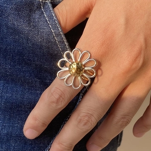 Detailed close-up of a two-tone daisy ring with a gold textured center on a denim background