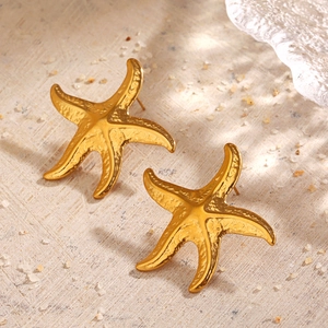 Golden starfish stud earrings with textured surface on a beach-themed background