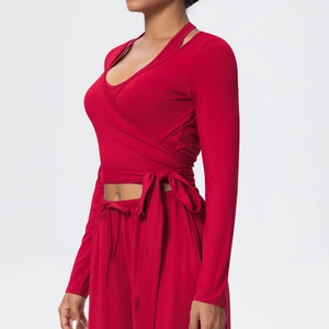 Detail of red wrap yoga top with waist tie and matching high-waist sports trousers