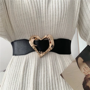 Elastic waist belt for women featuring a gold heart buckle over a black stretch band