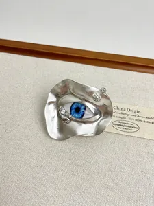 Macro detail of surrealist silver evil eye ring with blue iris and sparkling diamonds