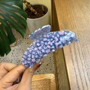 Close-up of blue and pink mosaic star pattern hair claw clip in a hand-held view