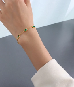 Détail du bracelet plaqué or 18 carats avec pierres vert émeraude porté au poignet