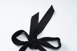 Close-up of black mesh halter dress showing detailed waist tie knot and fabric texture