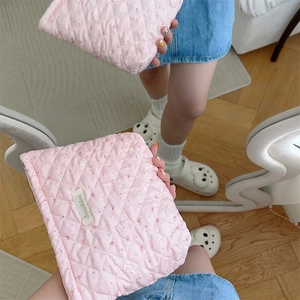 Detail view of pink quilted makeup bag with cute rabbit print held in a mirror selfie