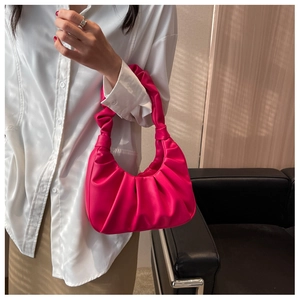 Detail of pleated design and knotted handle on a magenta crescent underarm bag