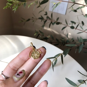 Detail of a gold hexagon pendant necklace with radial relief and a sparkling center zircon